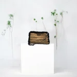 Zhanna Pochette crochetée en ficelle de jute beige gansée de fausse fourrure noire et bandoulière en cuir noir