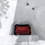 Zhanna Pochette crochetée en ficelle de jute bordeaux gansée de fausse fourrure noire et bandoulière en cuir noir