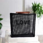 Lovana cabas de marché crocheté en ficelle de jute et grille polypropylène noires avec inscription LOVE brodé sur l'avant du sac et anses cuir marron camel